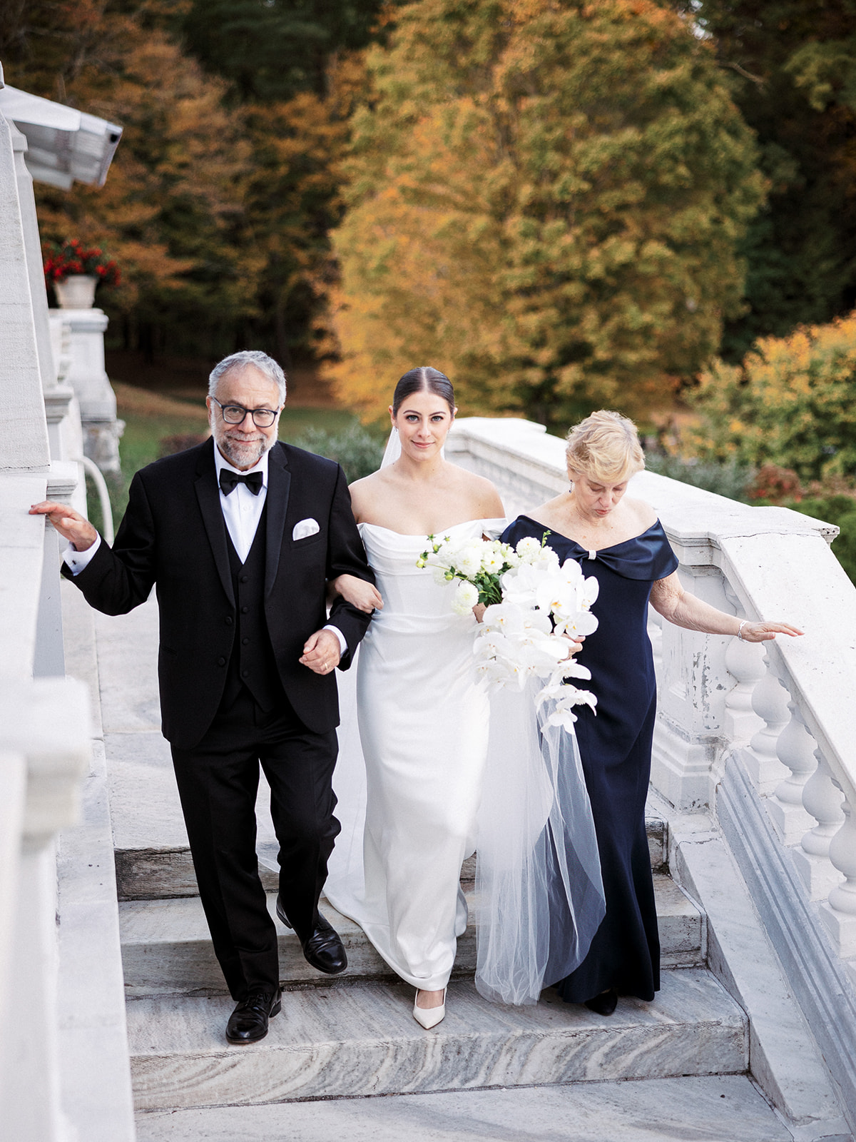 Bride gets escorted by parents down the aisle.