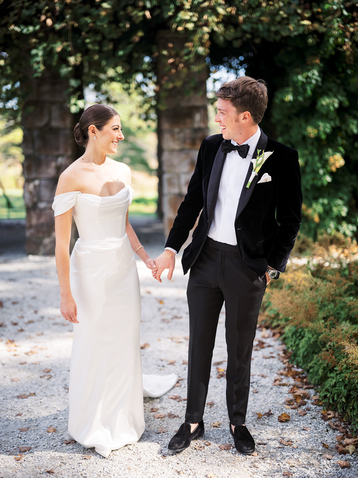 Bride and groom holding hands and smiling during first look moment under stone archway at The Mount