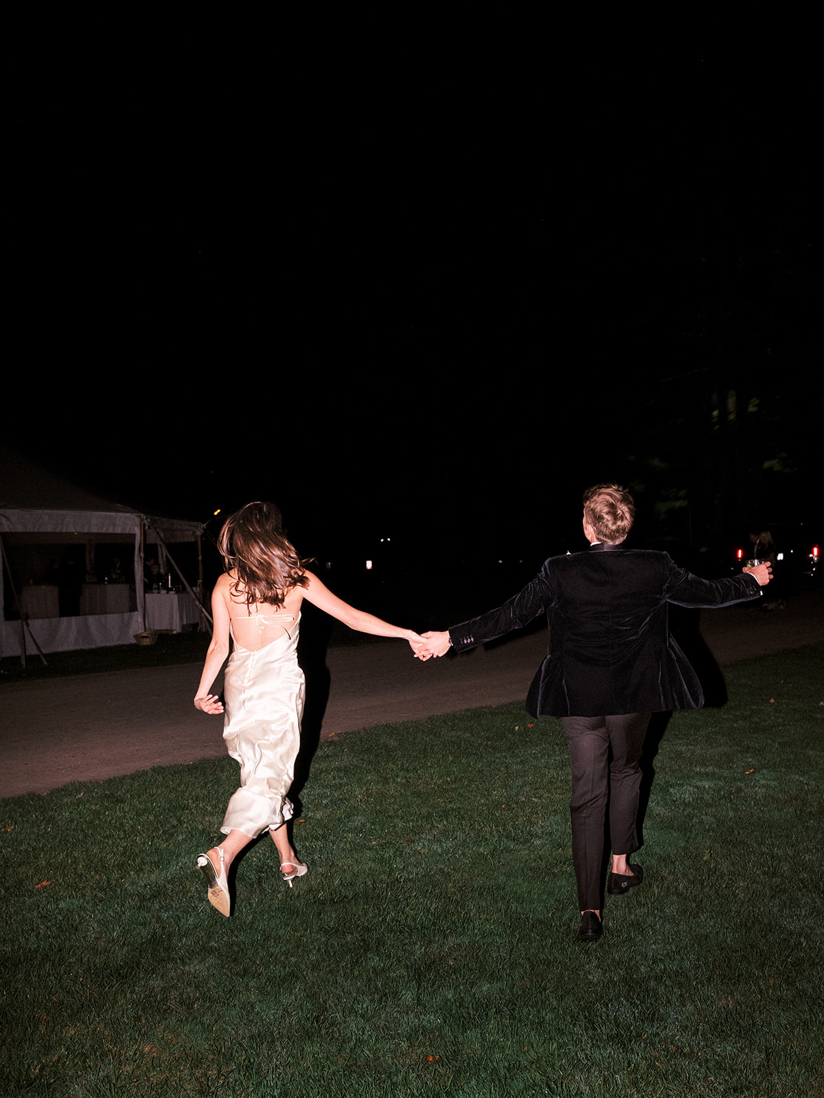Bride and groom skipping across the grass.