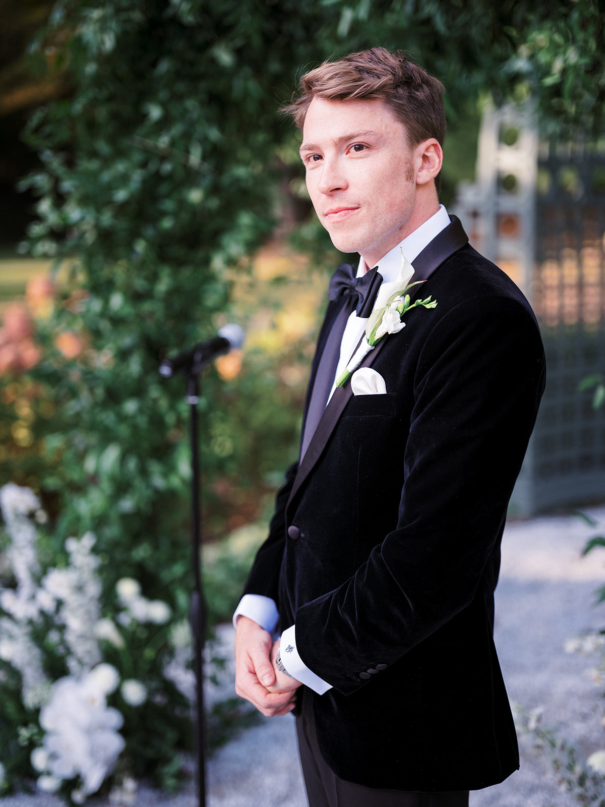 Groom standing at the altar in a velvet tuxedo, looking at the bride during the ceremony.
