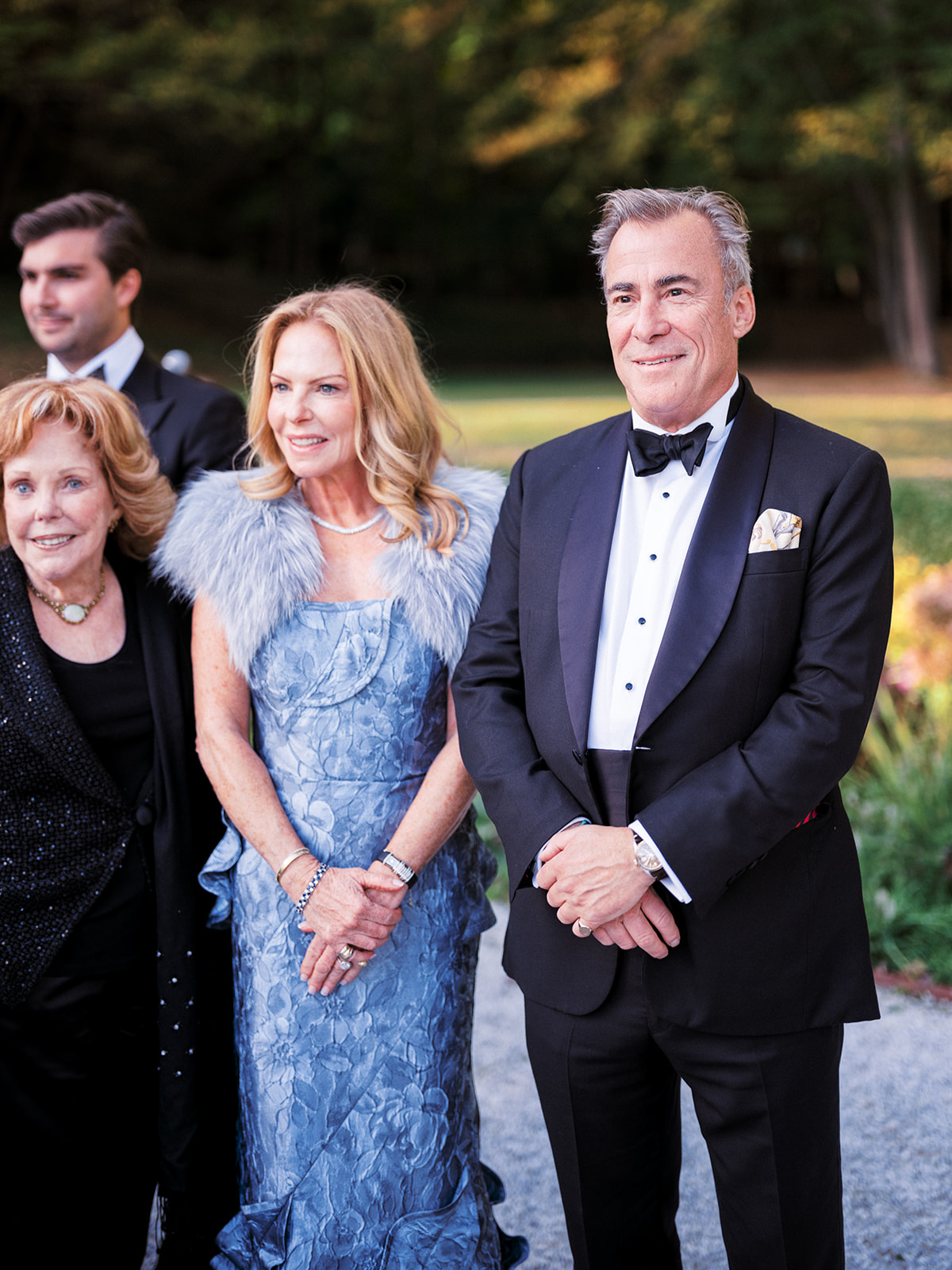 Parents of the groom dressed in formal attire, standing together and smiling before the ceremony.