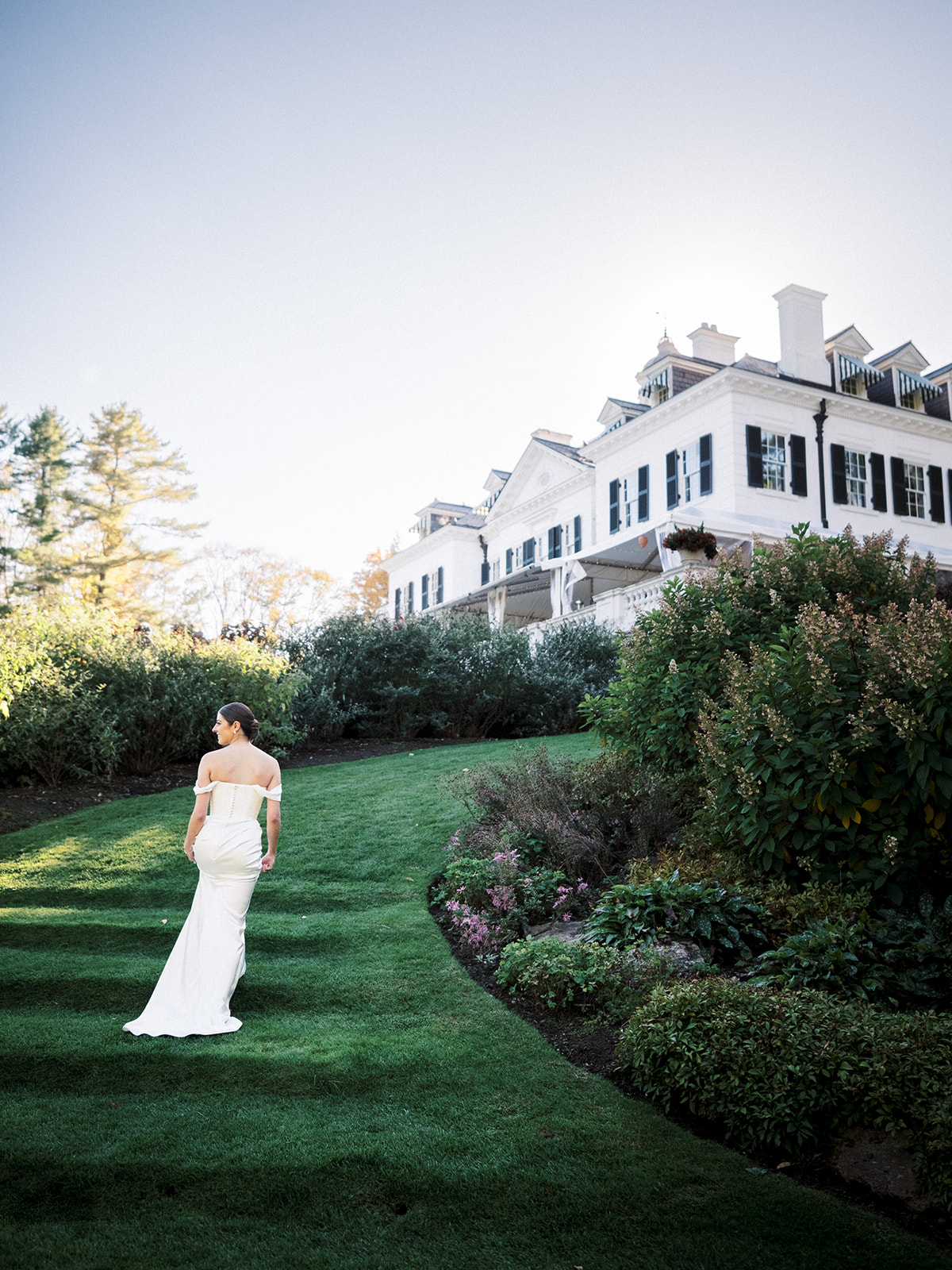 Wide-angle shot of couple walking along the top garden path at The Mount with lush greenery all around.