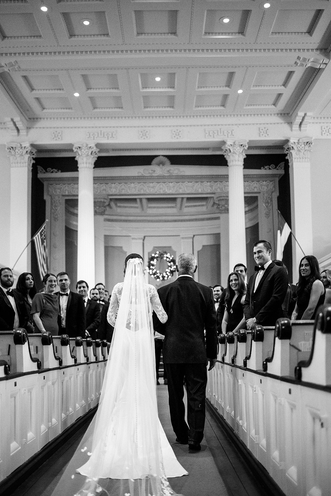 Back of the dress as the bride approach at the outdoor ceremony.