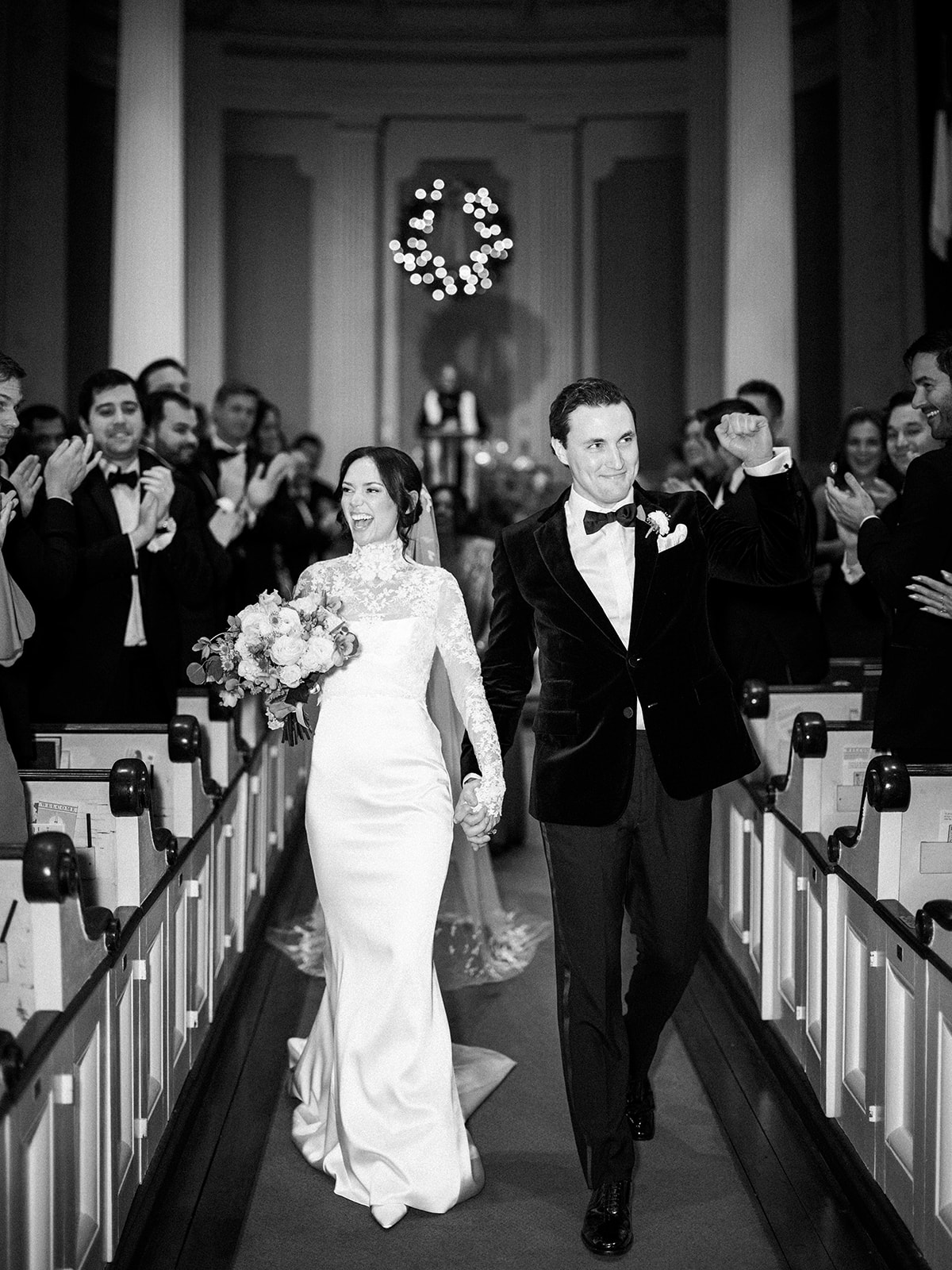 Black and white moment of the couple walking down aisle during ceremony.