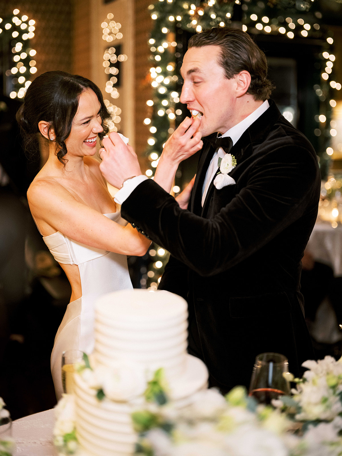 Bride and groom cutting their wedding cake together in front of guests.