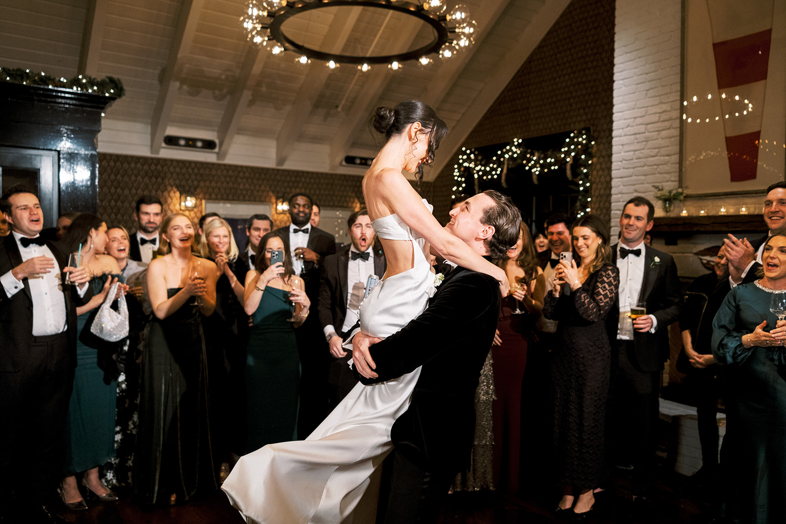 Bride and groom dancing in the center of a crowded, joyful dance floor.