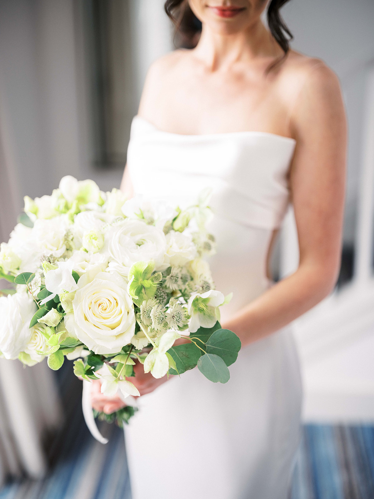 Bride holding flowers in soft morning light before her wedding at Baron's Cove.