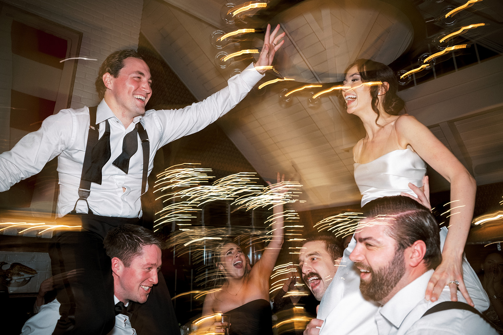 Bride laughing as she's lifted by guests in celebration.
