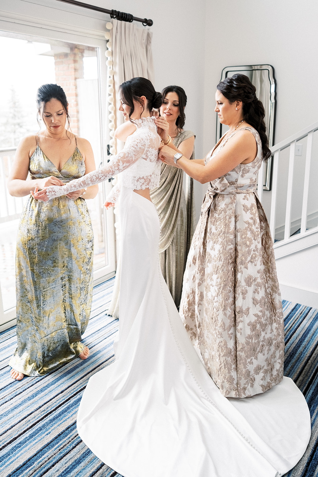 Bride stepping into her wedding dress surrounded by bridesmaids at Baron's Cove.