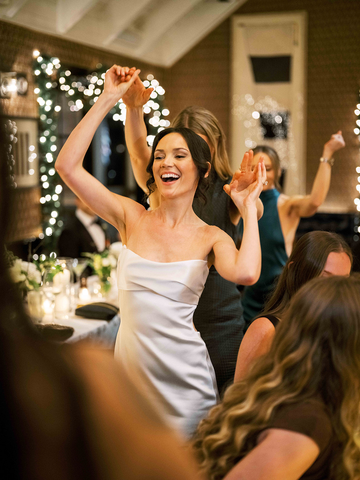 Bridesmaid dancing joyfully with her hands up during the reception at Baron's Cove.