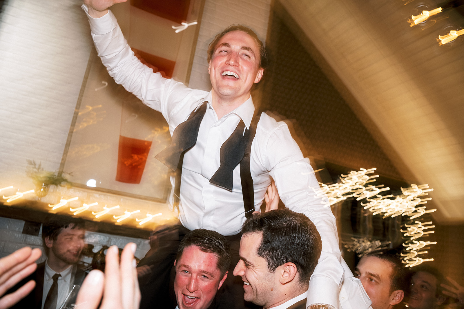 Groom lifted into the air by guests as the party hits peak energy.