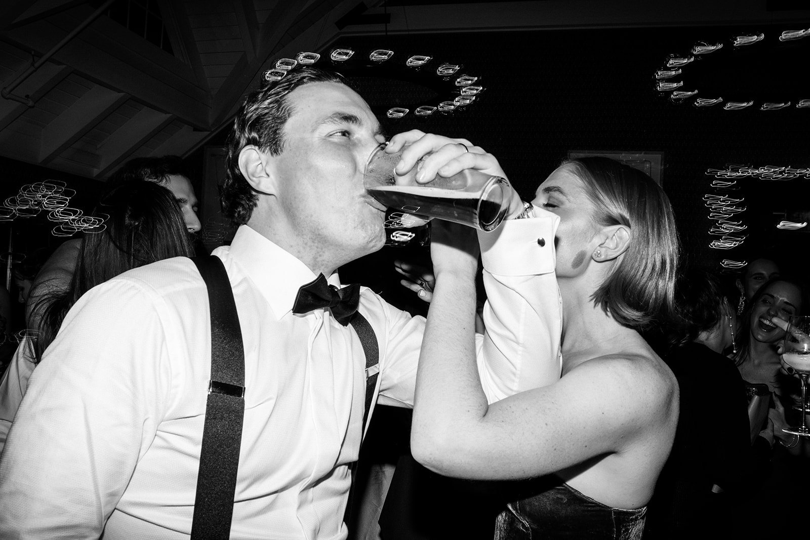 Guest pouring a drink directly into another’s mouth on the dance floor.