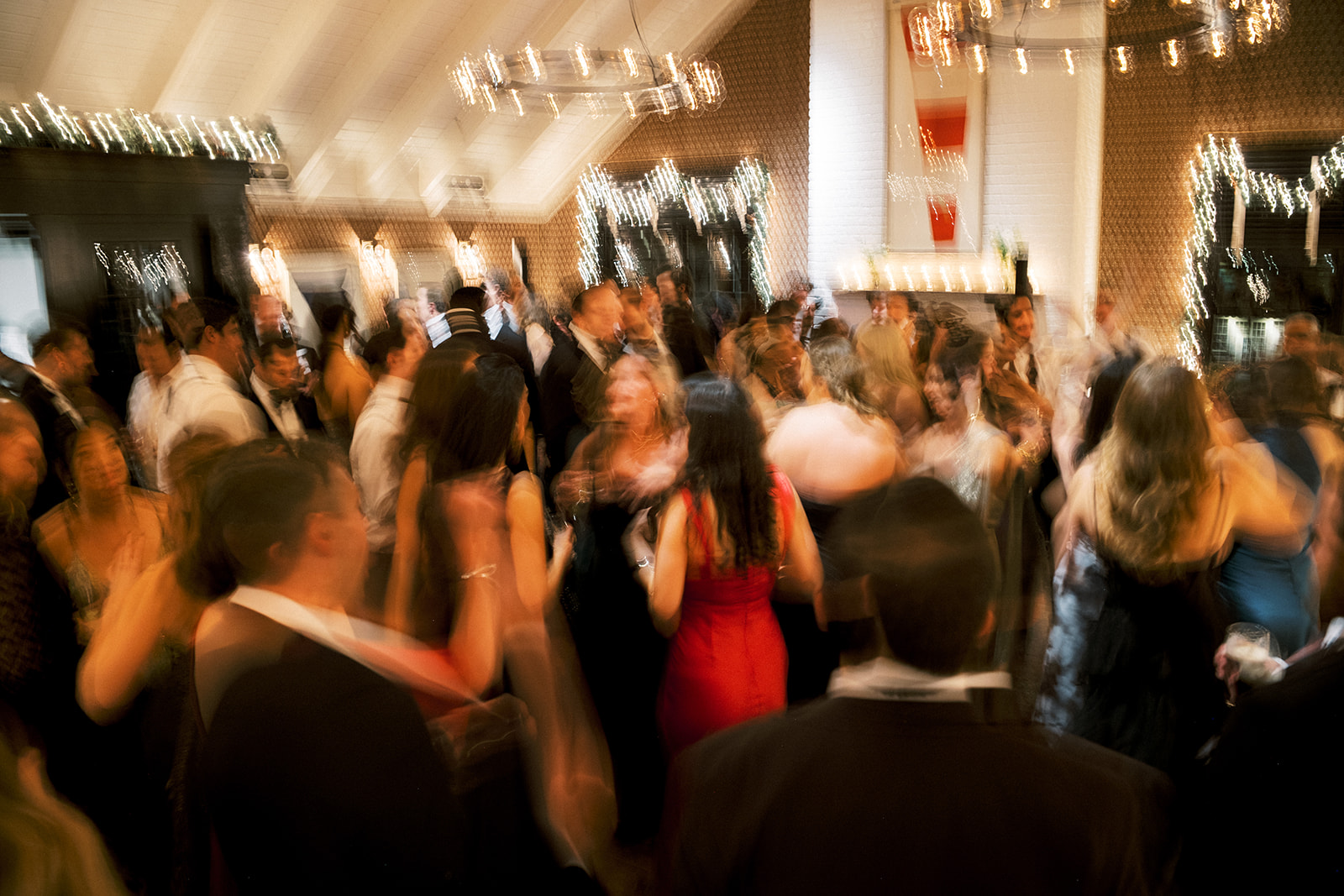 High-energy crowd dancing under chandeliers at Baron's Cove reception.