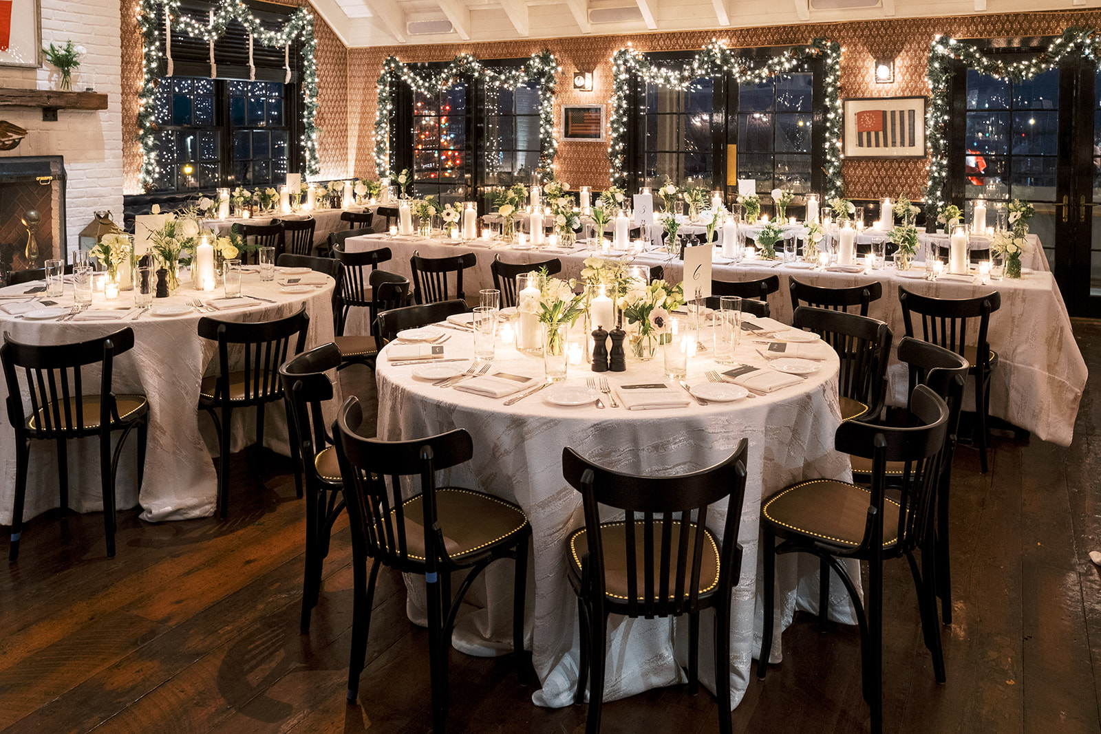 Reception table setting with gold flatware, floral centerpieces, and candlelight.