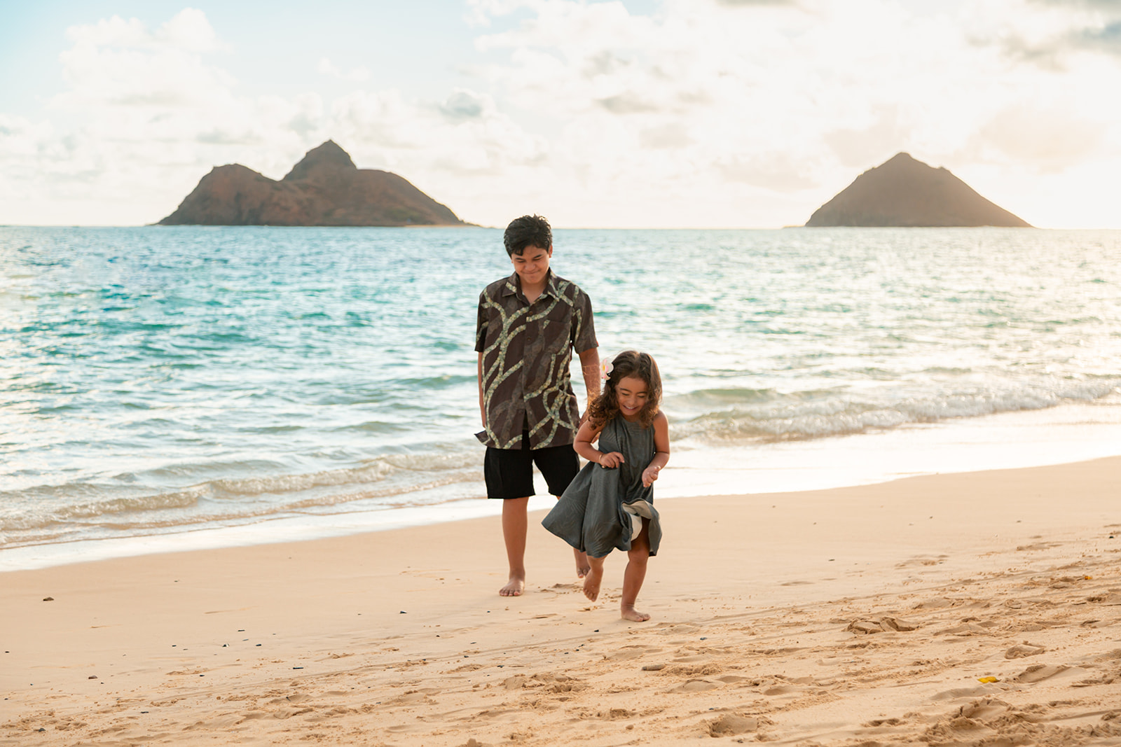 Kids playing on Lanikai Beach during a sunrise photo session with clear blue water.