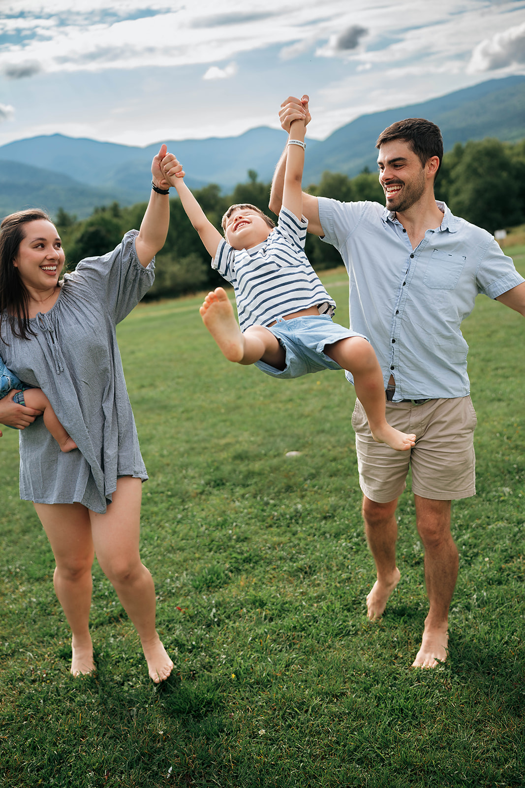 Parents swinging their son between them in a mountain meadow in Stowe, Vermont