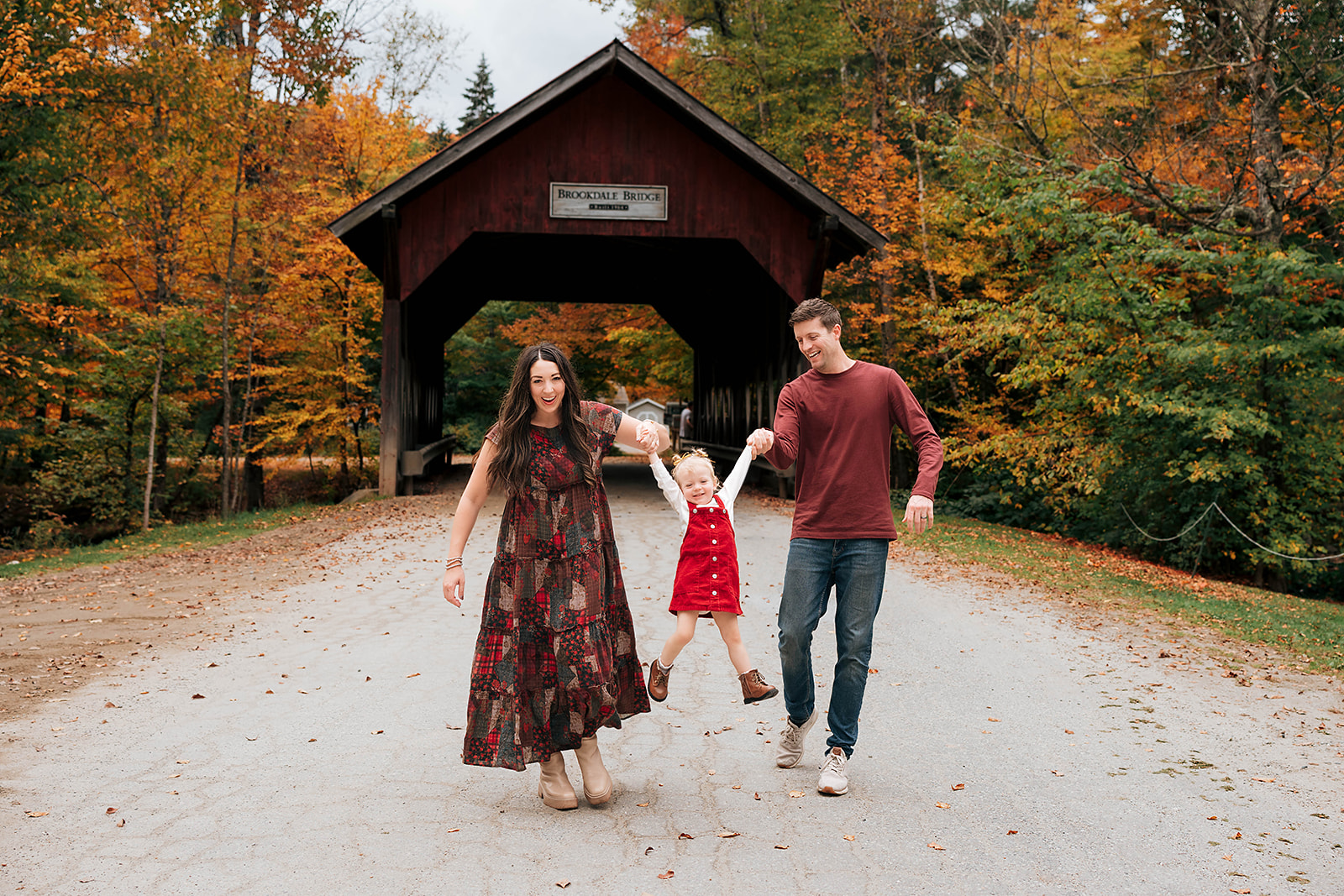 Family on a swing by a covered bridge in Stowe, Vermont